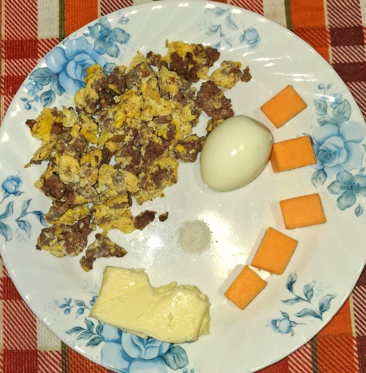 A typical Phase 1 carnivore protocol meal: scrambled ground beef and eggs, hard boiled egg, cheddar cheese, butter, and salt